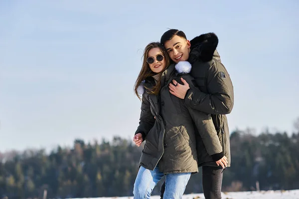 Счастливая пара обнимается и смеется на улице зимой — стоковое фото