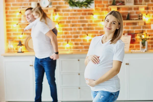 En ung familie, far, gravid mor og deres lille datter – stockfoto