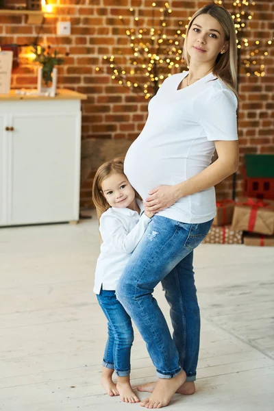 Um retrato de uma pequena filha com sua mãe grávida no — Fotografia de Stock