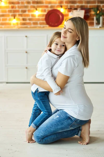 A portrait of a little daughter with her pregnant mother in the