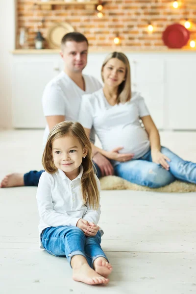 Una familia joven, padre, madre embarazada y su pequeña hija — Foto de Stock