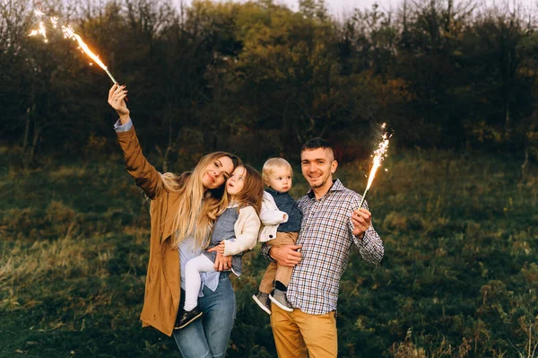 รูปภาพของครอบครัวที่มีความสุขที่มีแสงเบงกอลในสนามสีเขียว — ภาพถ่ายสต็อก