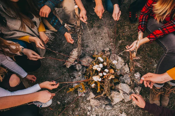 Un groupe d'amis sans visage fait frire des guimauves sur un feu de camp dans les bois. Vue du dessus. — Photo