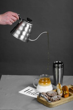 İnsan eli, gri arka plandaki ince bir deredeki kaba kahve döker..