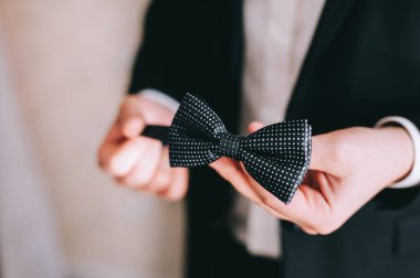 Damat elinde papyon tutuyor, giyiniyor ve düğün törenine hazırlanıyor..