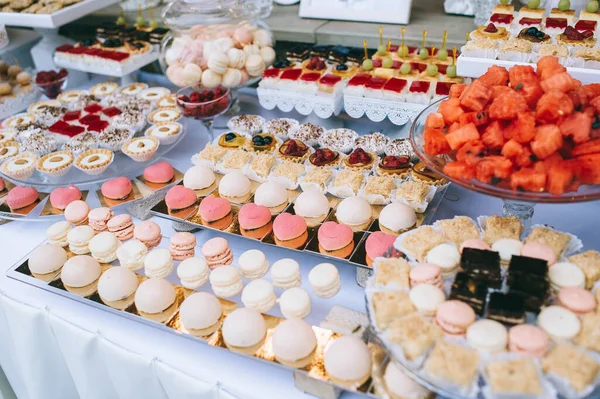 Wedding candy bar with different colored bright cupcakes, macaroons, cakes, jelly and fruits. — Stock Photo, Image