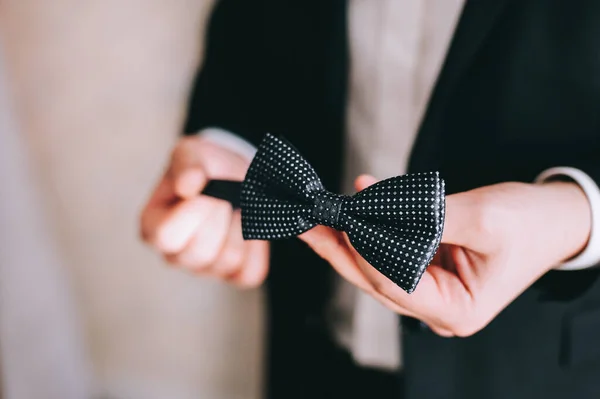 Groom segura um laço em suas mãos, se veste e se prepara para a cerimônia de casamento. — Fotografia de Stock