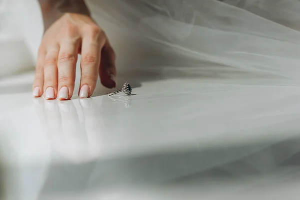 Primer plano de la mano de la novia con manicura y un anillo vintage con un diamante azul en el alféizar de la ventana. —  Fotos de Stock