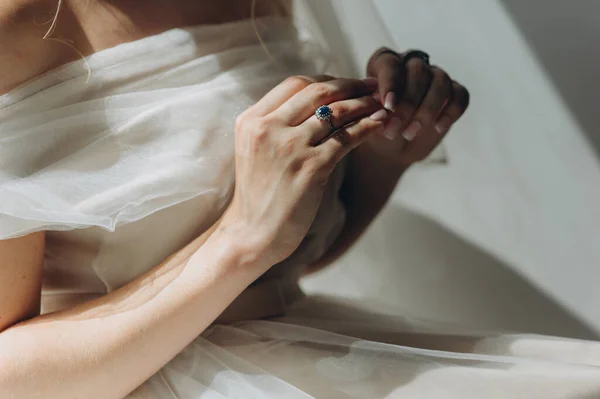 Primo piano di un anello di nozze vintage con un diamante blu sul dito spose in un abito da sposa lucido. — Foto Stock