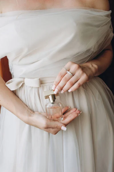 Zbliżenie eleganckie perfumy w szklanej butelce w rękach panny młodej w sukni ślubnej. — Zdjęcie stockowe