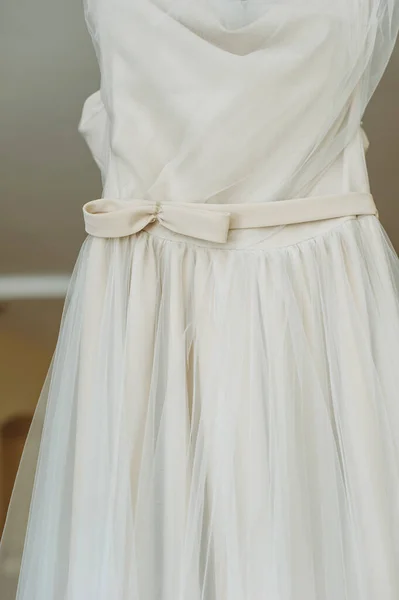 Close up of a minimalist bow on a beautiful white minimal handmade wedding dress hanging on a hanger