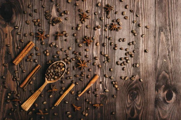 Vista superior de cuchara vintage de madera, granos de café, canela y anís estrellado sobre fondo de madera. — Foto de Stock
