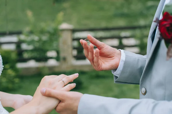 Les mains des mariés dans le processus solennel d'échange d'anneaux symbolisant la création d'une nouvelle famille — Photo