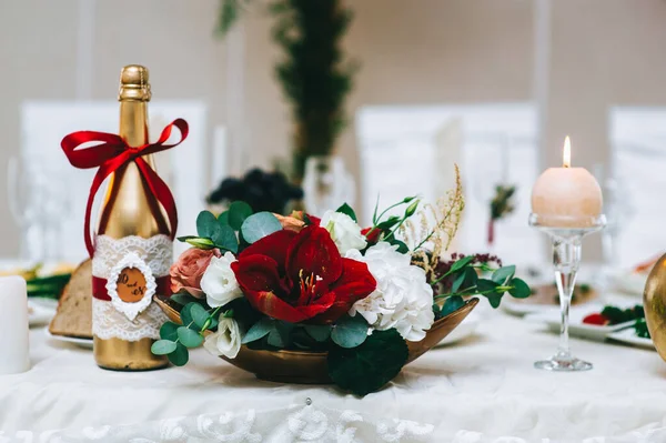El primer plano de un arreglo floral en tonos rojos en un soporte de oro se encuentra sobre una mesa. — Foto de Stock