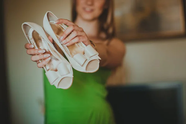 Dama de honor sosteniendo zapatos de boda en sus manos delante de ella. —  Fotos de Stock