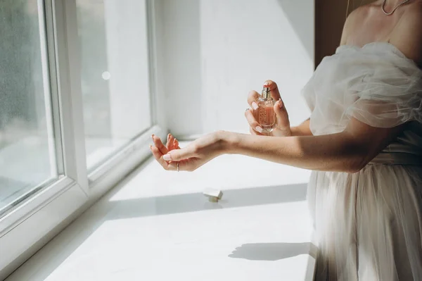 Роскошный безликий жених распыляет элегантные духи на руку в комнате у окна. — стоковое фото