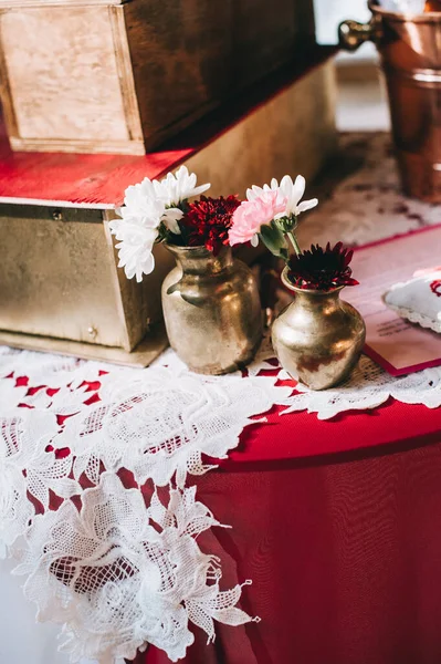 Fleurs dans de petits vases vintage de couleur dorée sur une table rétro vintage avec une nappe rouge et blanche. — Photo