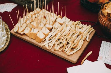 Dilimlenmiş farklı peynir parçalarıyla dolu tahta bir tahtanın yan görüntüsü. Yemek servisi..