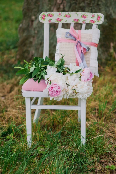 Tuindecoratie met verse pioenrozen op een roze retro op een stoel. — Stockfoto