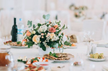 Güllü buket, Eustoma ve okaliptüs yapraklı. Çiçeklerle süslenmiş düğün masası.