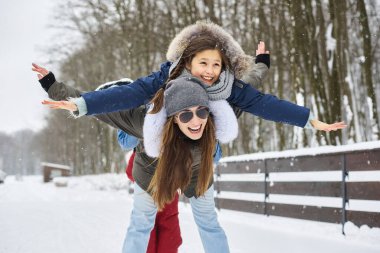 Genç bir anne ve ağaç çocukları eğleniyor ve evin yakınında dışarıda oynuyorlar.