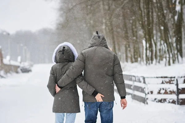 A beautiful young couple in love walking through winter park — Stock Photo, Image