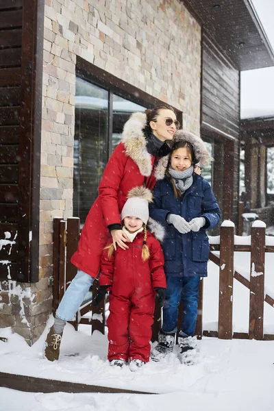 Eine junge Mutter mit ihren drei Kindern vergnügt sich beim Schneeballspielen im Freien in der Nähe des Hauses — Stockfoto