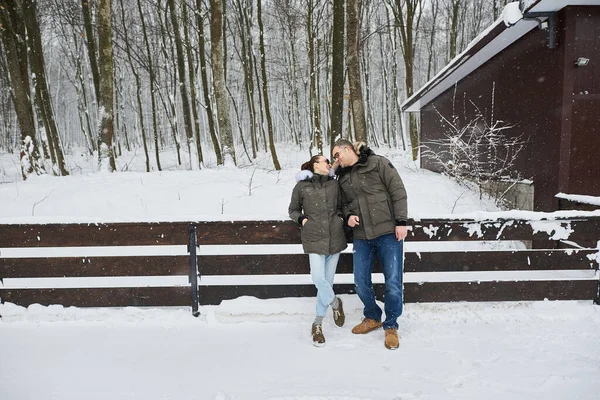 A beautiful young couple in love walking through winter park in snowfall — Stock Photo, Image