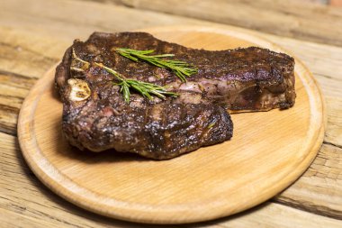 Kesme tahtası koyu ahşap arka plan üzerinde ızgara T-Bone biftek