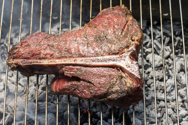 Bir üst sığır filetosu t kemik biftek alev üzerinde bir barbekü ızgara