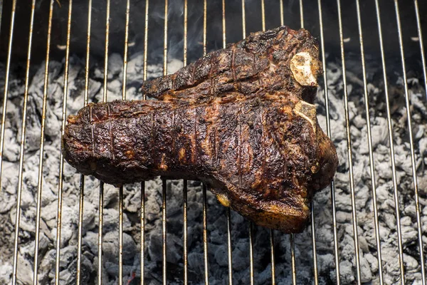 Bir üst sığır filetosu t kemik biftek alev üzerinde bir barbekü ızgara