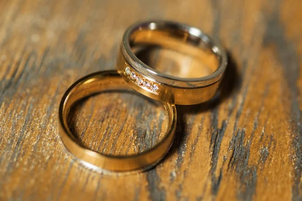 Detalles de la mañana del día de la boda. dos anillos de boda de oro están en la mesa de madera marrón — Foto de Stock