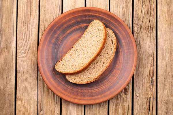 Тарелка с ломтиками черного хлеба на старинном деревянном столе — стоковое фото