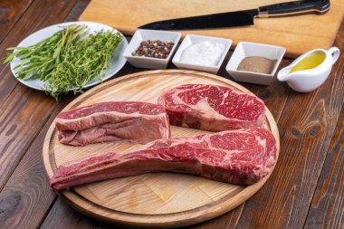 Baharat masajı, taze biberiye ve siyah mutfak bıçağı ile ızgara malzemeli çiğ baltalı biftek.