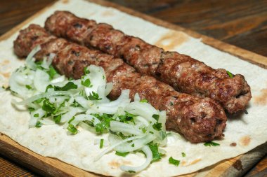 Tahta bir yüzey üzerinde otlu lula kebabı