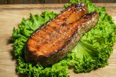 Ahşap tahtada taze salata ile ızgara somon bifteği.