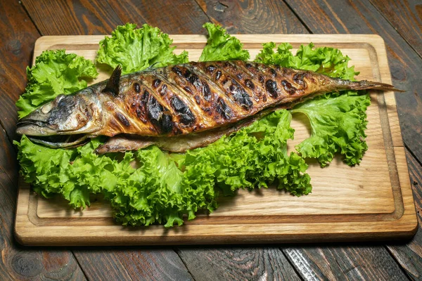 Caballa a la parrilla en una tabla de madera con ensalada —  Fotos de Stock