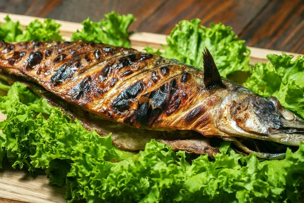 Caballa a la parrilla en una tabla de madera con ensalada —  Fotos de Stock