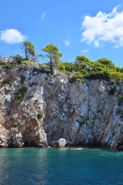 Yeşillik, kalın ormanlık ve turkuaz tropikal sularla dolu güzel bir Yunan adası manzarası. Dağlar, yoğun yeşil ormanlar, beyaz kayalar ve berrak mavi sular, cennet gibi seyahat noktalarını oluşturur..