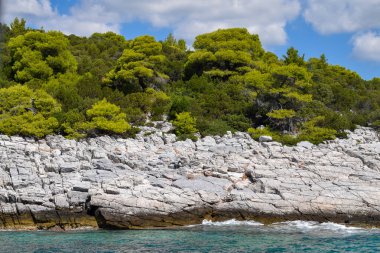 Yeşillik, kalın ormanlık ve turkuaz tropikal sularla dolu güzel bir Yunan adası manzarası. Dağlar, yoğun yeşil ormanlar, beyaz kayalar ve berrak mavi sular, cennet gibi seyahat noktalarını oluşturur..