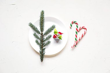 Düz tatil tablo ayarı dekorasyon, xmas yatıyordu. Bir tabak beyaz masa, bazı lolipop ve bir küçük hediye kutusu.