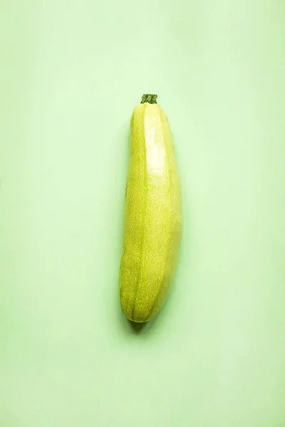 緑の紙の背景に新鮮なズッキーニ 精進料理 — ストック写真