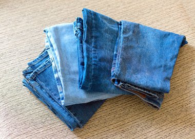 Kanepede birkaç katlanmış denim kıyafetlerim. Mavi denim kumaş tonları.