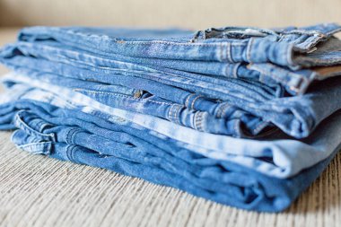 Kanepede birkaç katlanmış denim kıyafetlerim. Mavi denim kumaş tonları.