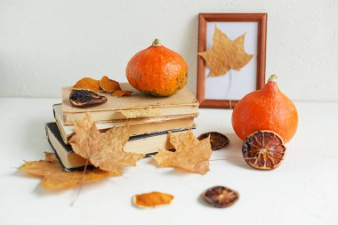 Sonbahar bileşimi kuru sarı akçaağaç yaprakları, Turuncu kabak ve beyaz arka plan üzerinde eski kitaplar
