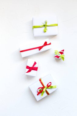 Noel natürmort beyaz beton zemin üzerinde. Küçük hediye kutuları yeşil ve kırmızı şeritler, üstten görünüm alanı Kopyala.