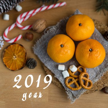 Noel hala dekore köknar ağacı dalları, şekerleme, lolipop ahşap arka plan üzerinde taze ve olgun mandalina ömrünü. Kare görüntü. Metin 2019 yıl