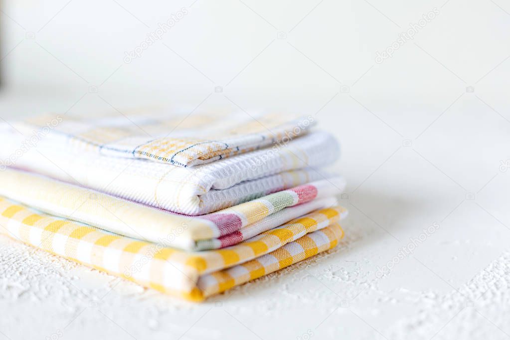 A pile of colorful cotton knapkins on white concrete background. A part of kitchen interior. Copy space.