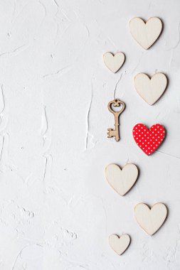St. Valentine's gün arka plan ile bir küçük anahtar ve beyaz masa ahşap kalpler. Üstten görünüm, tatil kavramı.