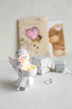 Küçük melek şamdan Mum ve kutuları, beyaz beton zemin üzerine cam kalpleri ile natürmort. Tatil kavramı, tebrik kartı.